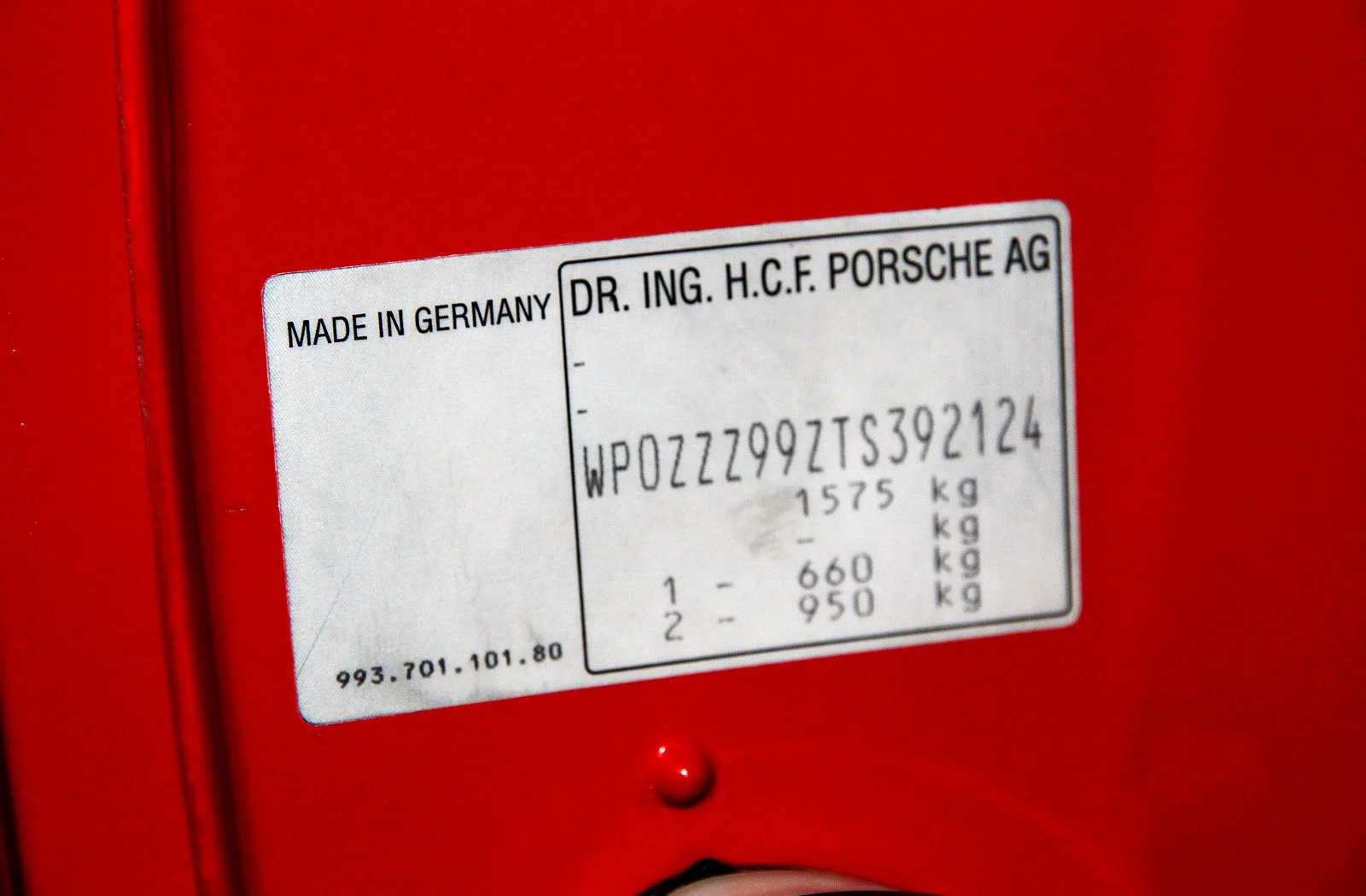 Porsche vehicle identification number plate showing VIN and weight specifications on red car door