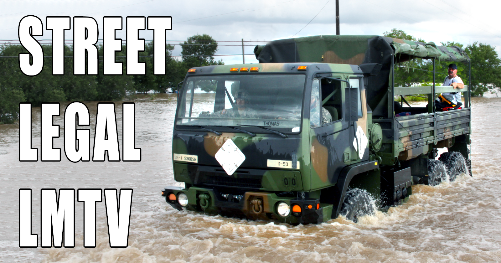 Military surplus LMTV truck fording through floodwaters with passengers
