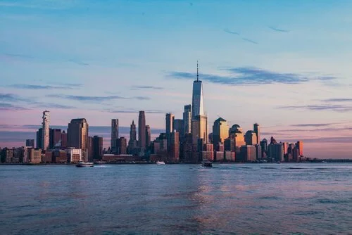 New York City skyline at sunset showing why residents consider out-of-state car registration to avoid inspections