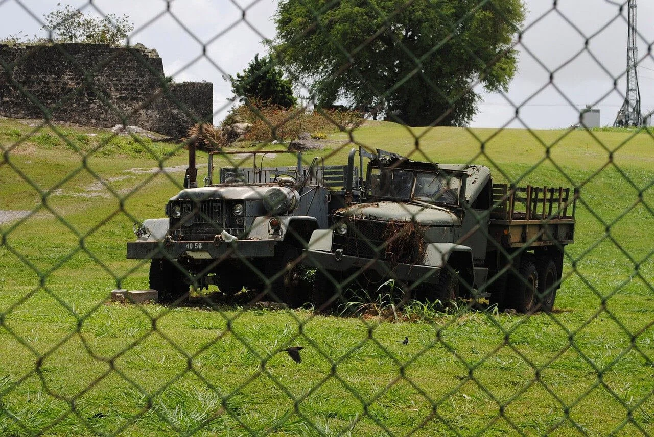 Vintage military 2.5 ton trucks parked on grass field for overlanding adventure conversion project