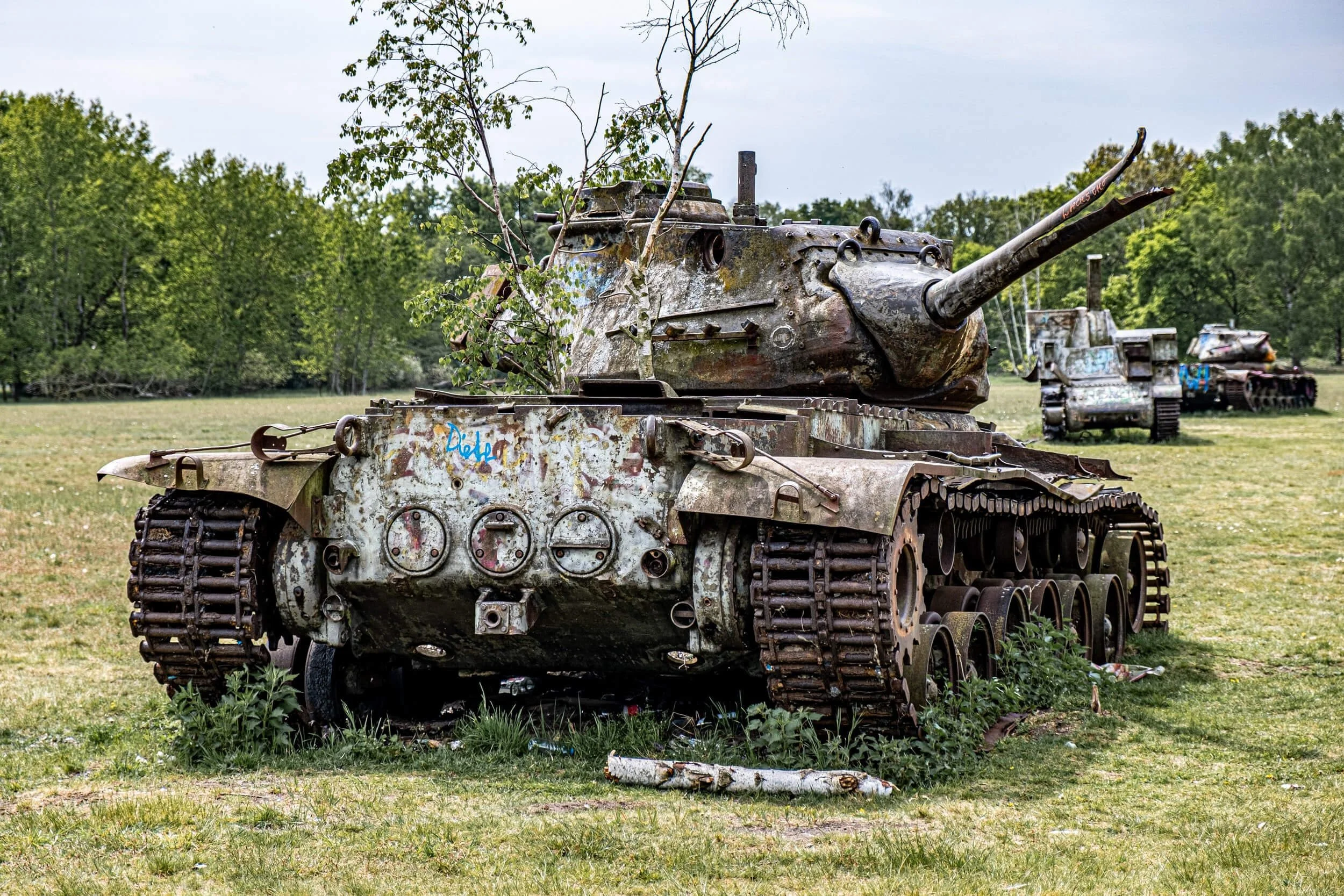 Abandoned rusted military tank with turret in overgrown field