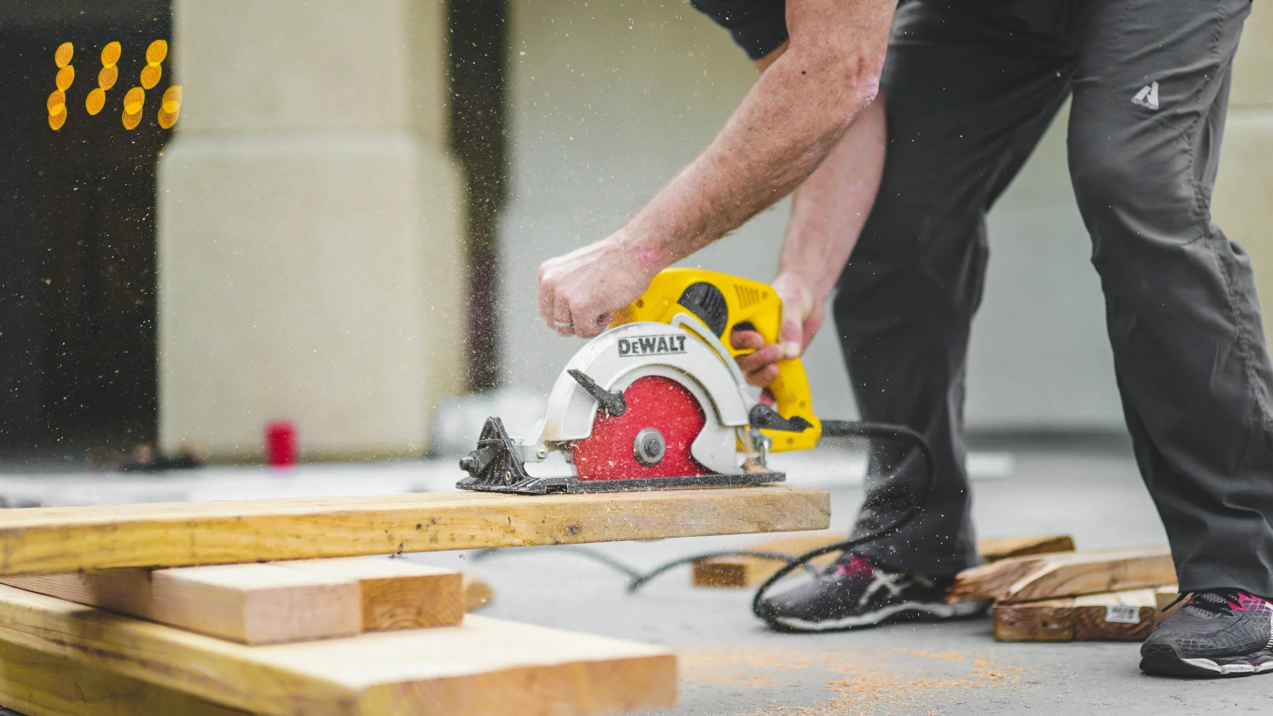 Worker using yellow DeWalt circular saw cutting wood lumber on construction site in Montana