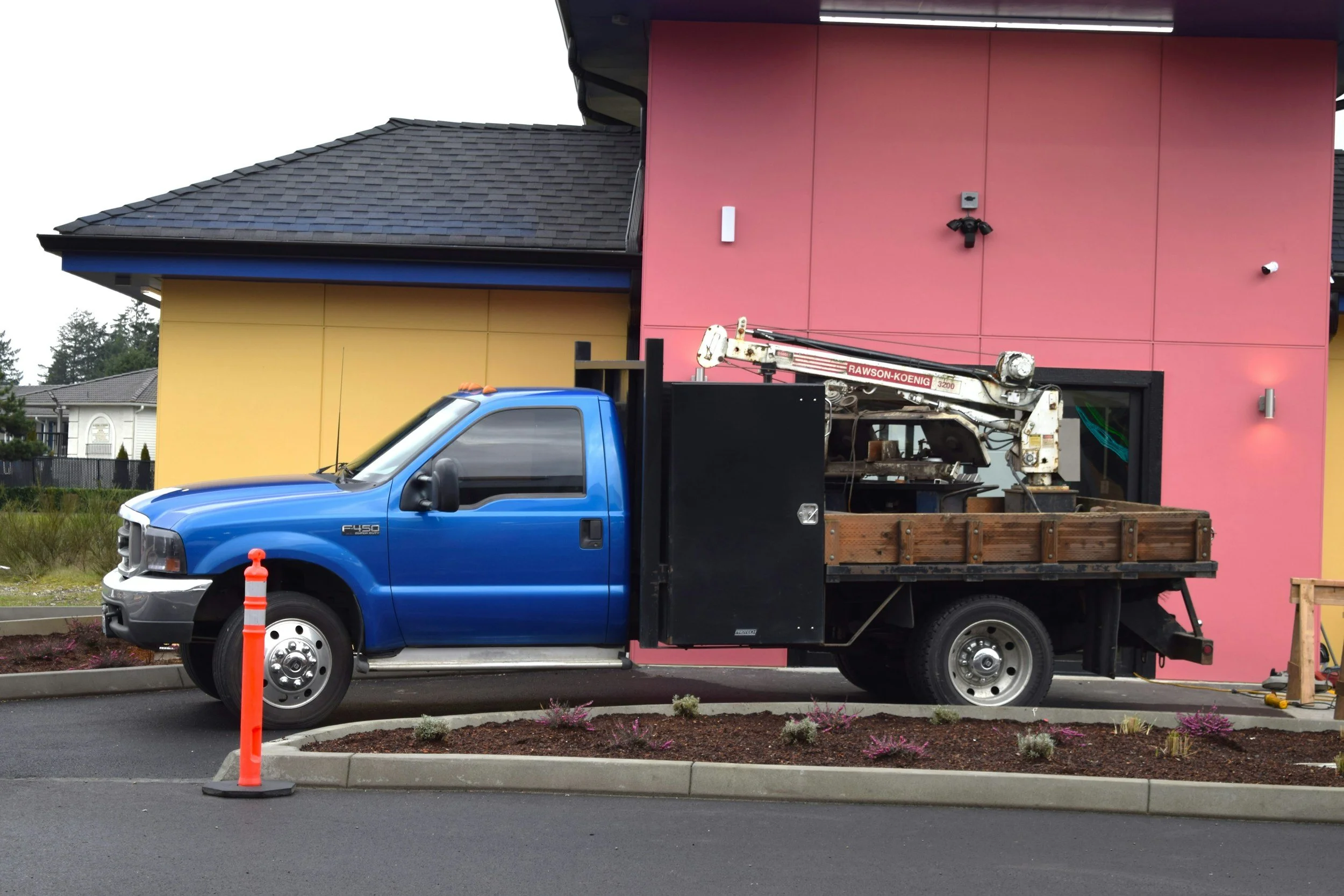 Blue Ford F-450 dump truck with crane parked at commercial building, representing tradesman vehicle registration solutions.