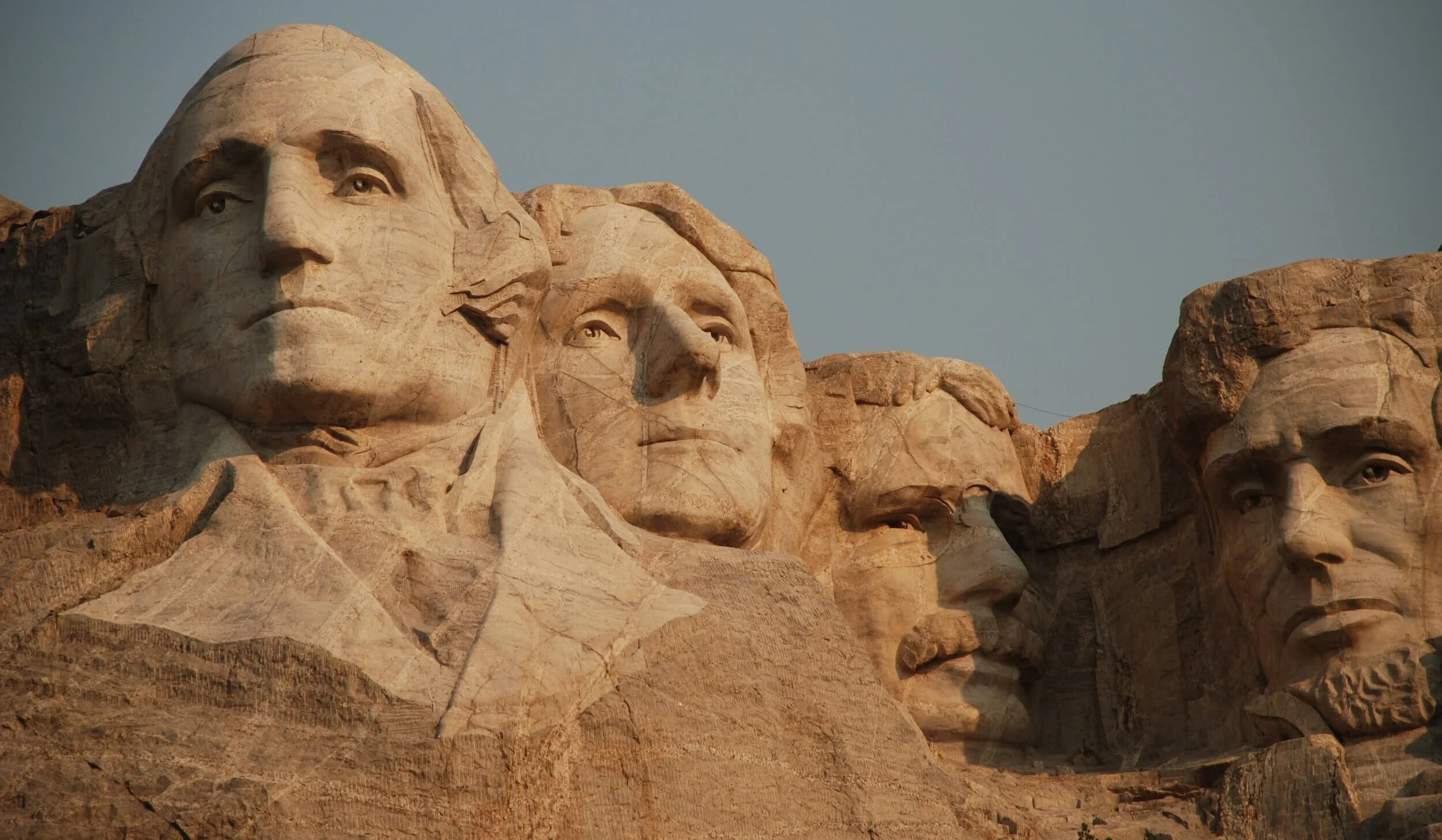 Mount Rushmore monument featuring four carved presidential heads in stone against clear blue sky