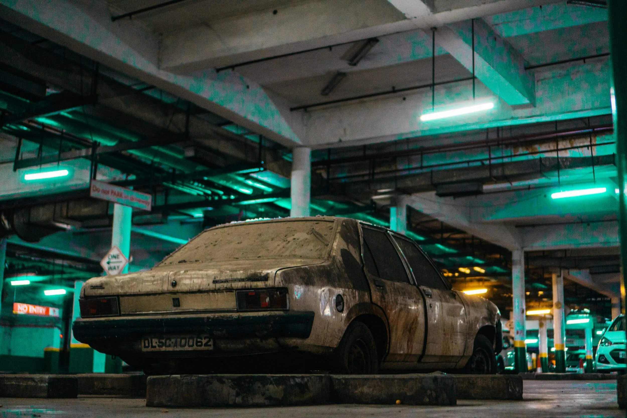 Abandoned rusty car in parking garage with branded title, demonstrating vehicle deemed unfit for road use