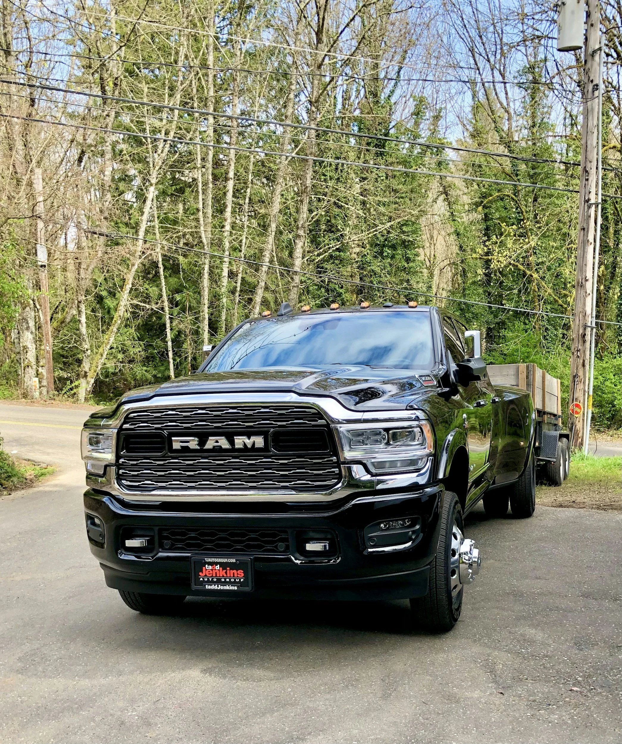 Black RAM pickup truck with flatbed trailer parked on residential street for hot shot trucking business startup