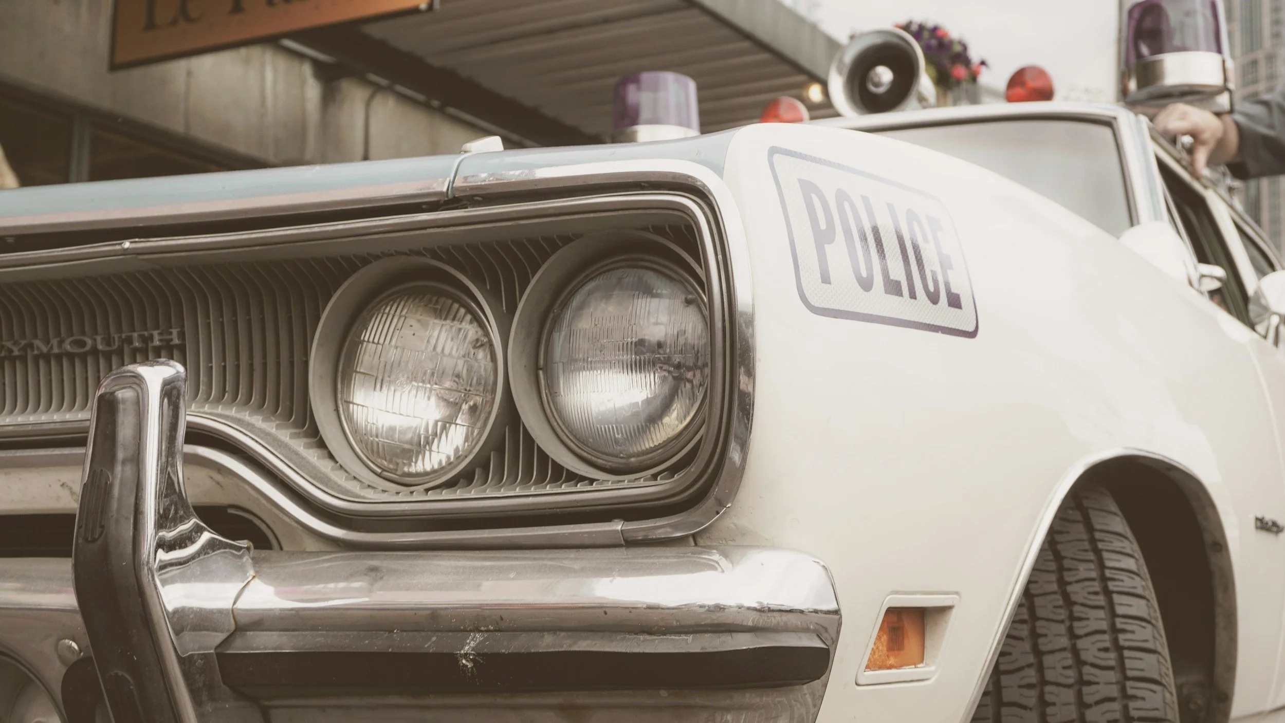 Vintage white police car with dual headlights displayed in garage