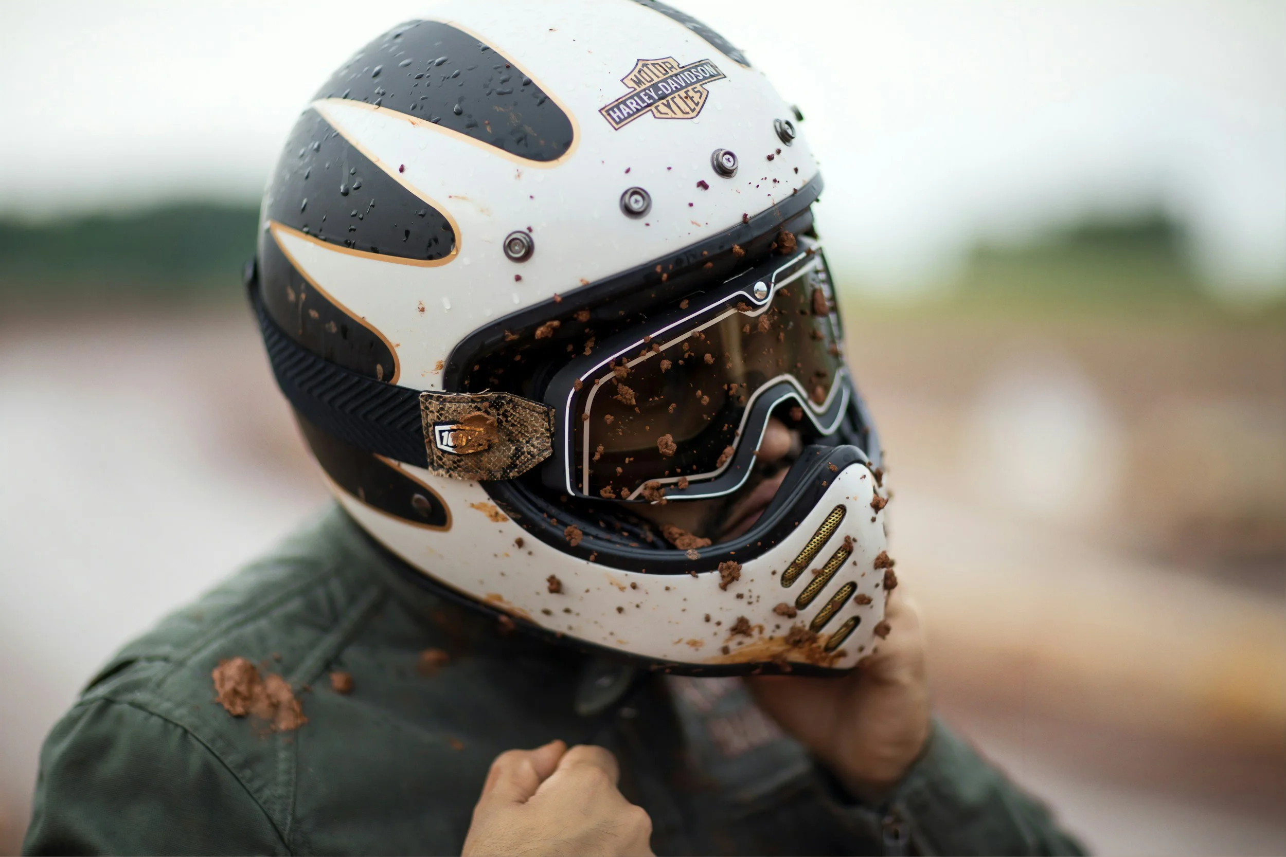 Muddy off-road dirt bike helmet worn by rider in outdoor trail setting during riding session