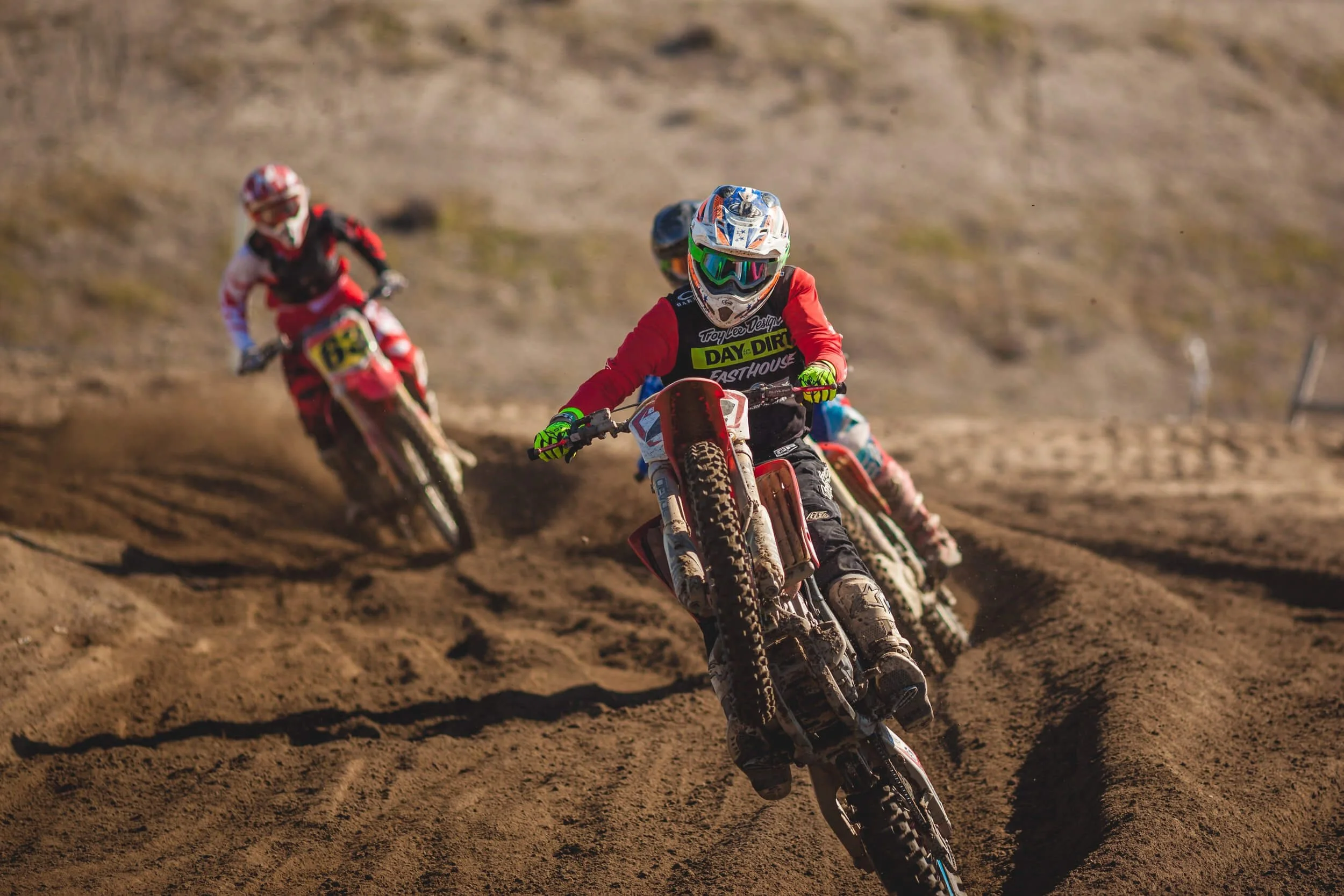 Dirt bike riders racing on sandy terrain, demonstrating off-road riding skills for California registration requirements.