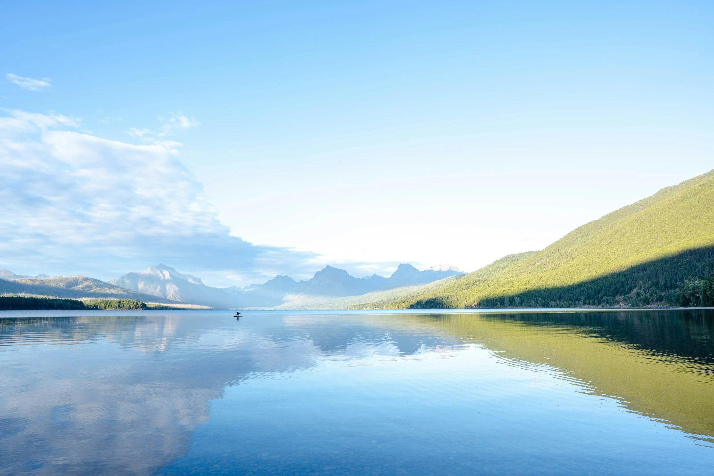 Serene Montana lake with mountain reflections, forested shores and clear blue waters