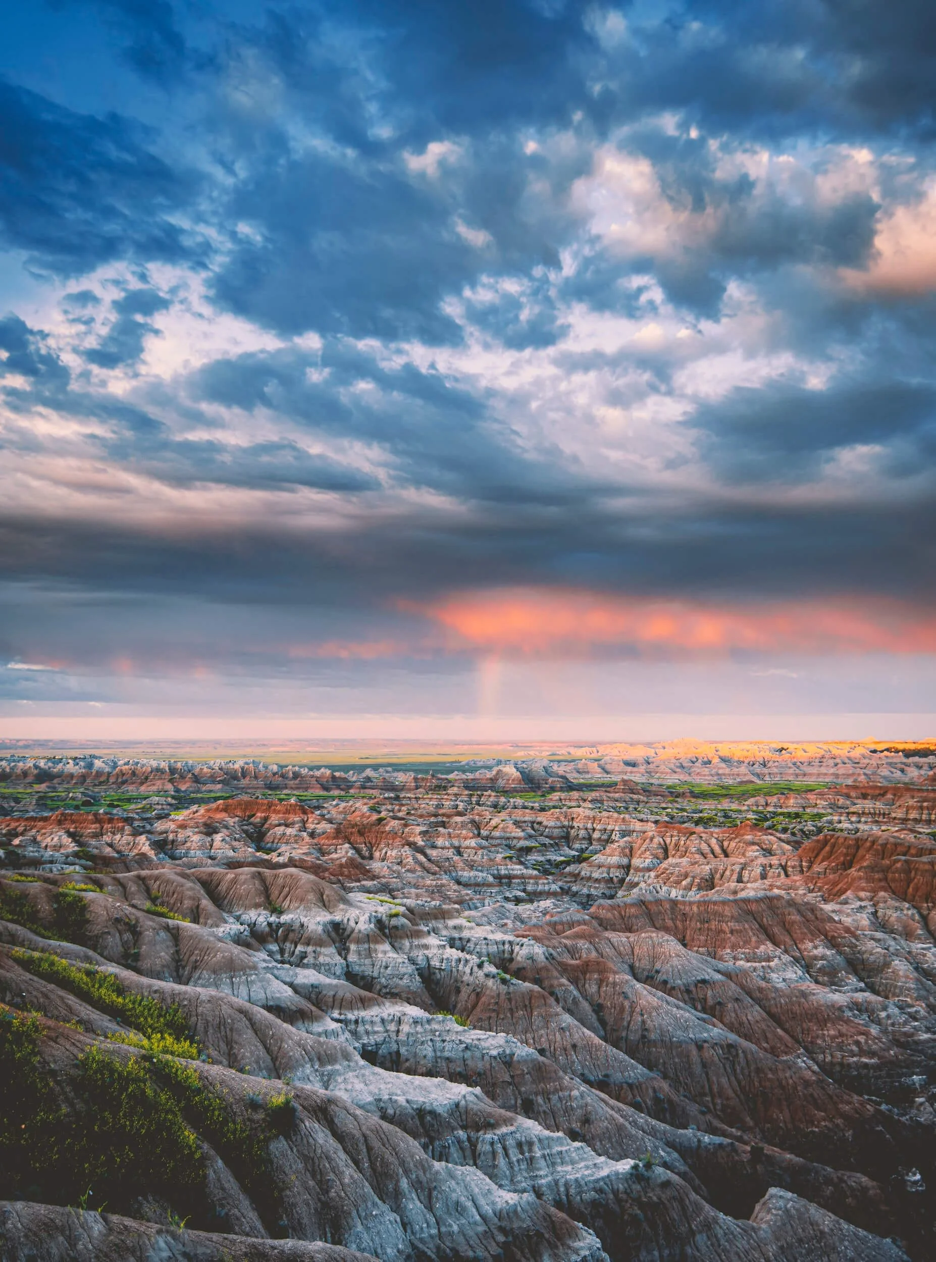 Badlands landscape at sunset showing colorful rock formations and vast terrain under dramatic sky