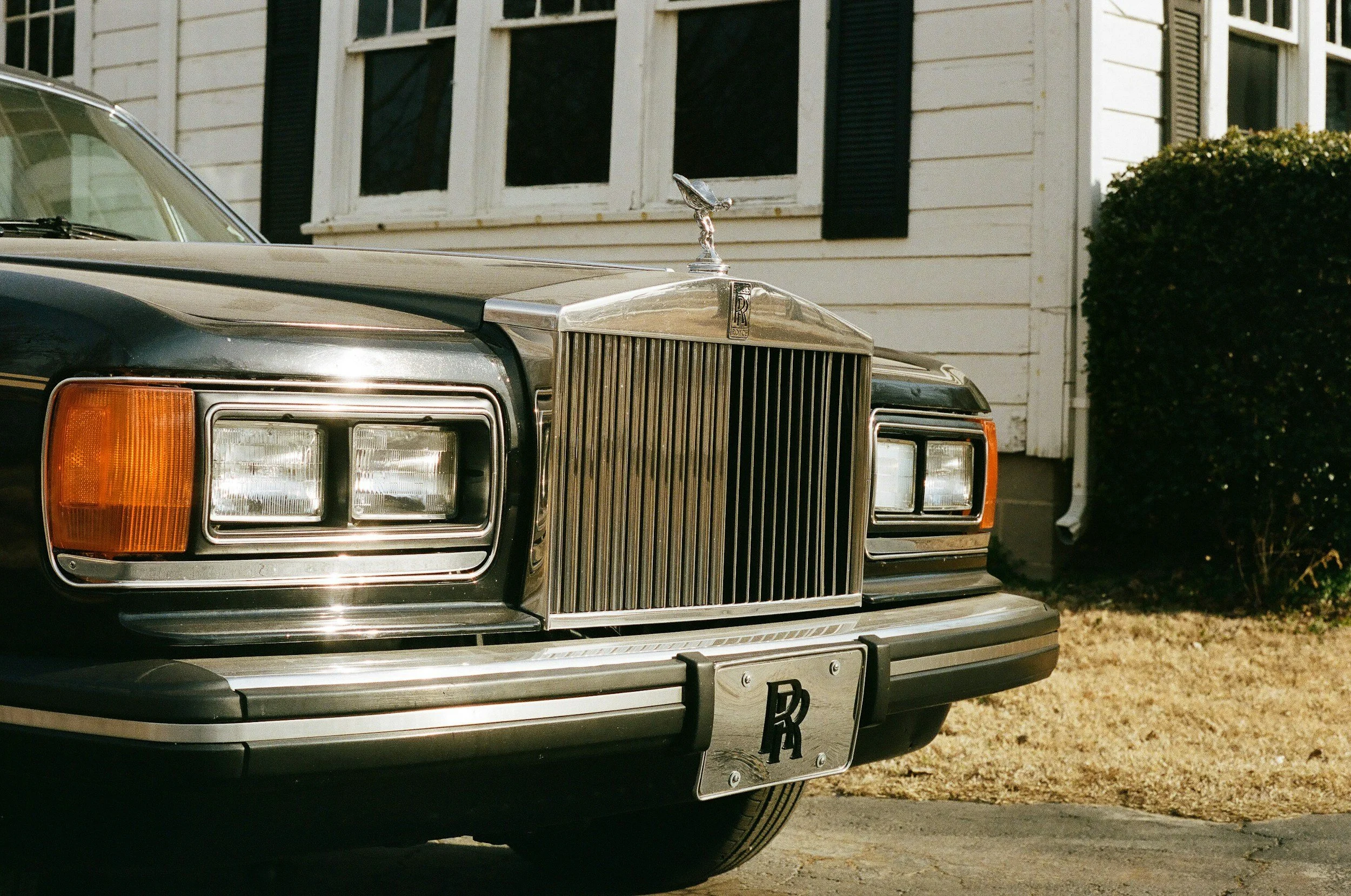 Elevated Rolls-Royce automobile parked in front of elegant estate home