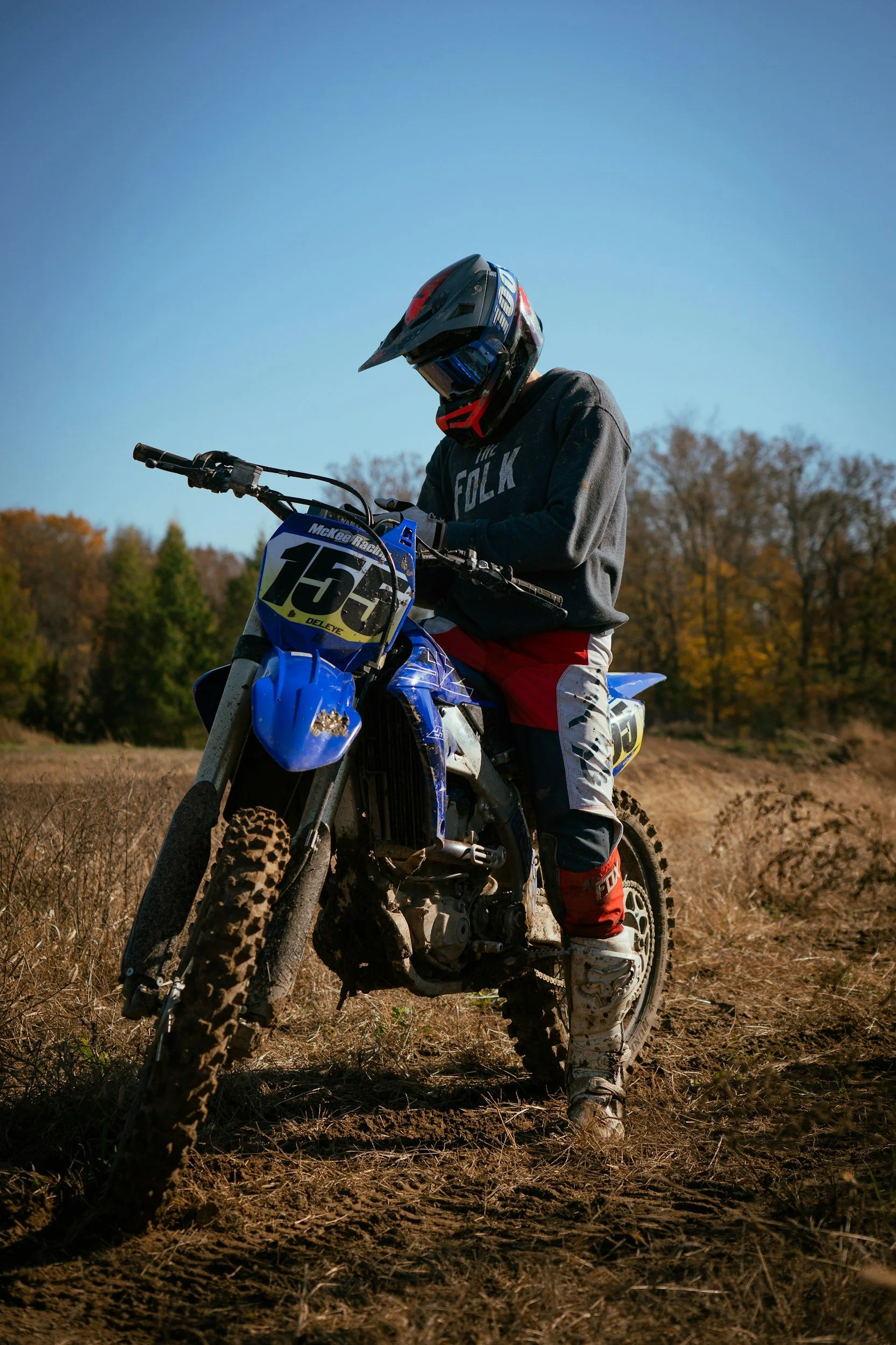 Dirt bike rider on blue motocross bike in muddy field, representing 2025 off-road riding trends and innovations