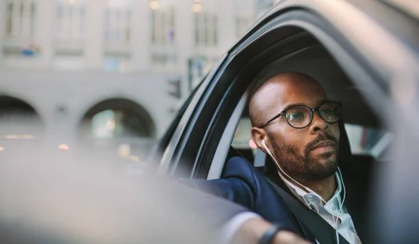 Professional man wearing glasses in car window, representing diverse driver registration needs and vehicle ownership