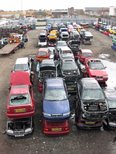 Donated cars in a salvage yard awaiting processing for charity vehicle donation programs and recycling