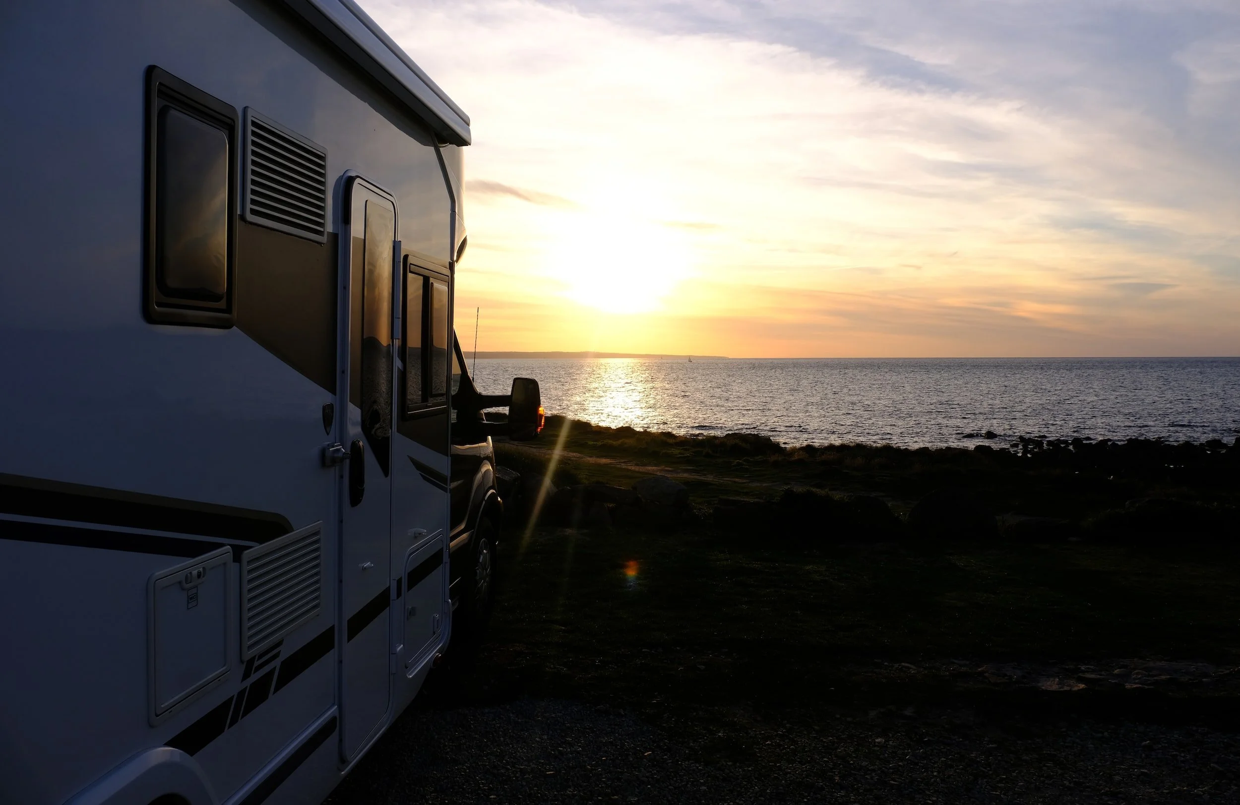 RV parked at sunset beach campground overlooking ocean water and coastline landscape
