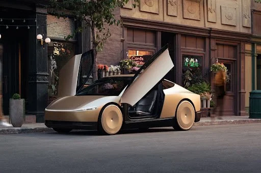 Futuristic beige and black concept robotaxi vehicle with gull-wing doors open on urban street