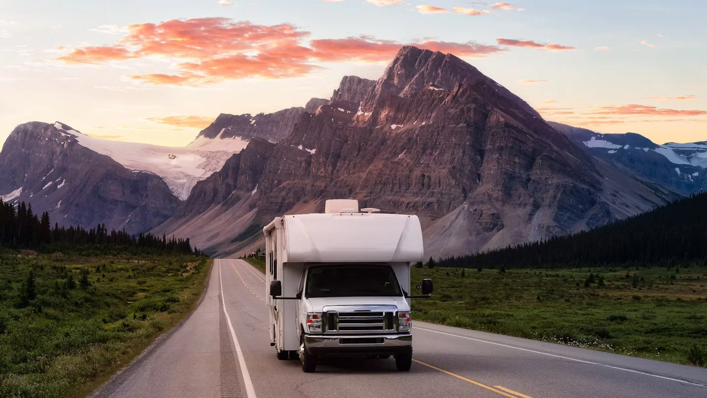 White RV motorhome driving mountain road at sunset for scenic road trip adventure planning