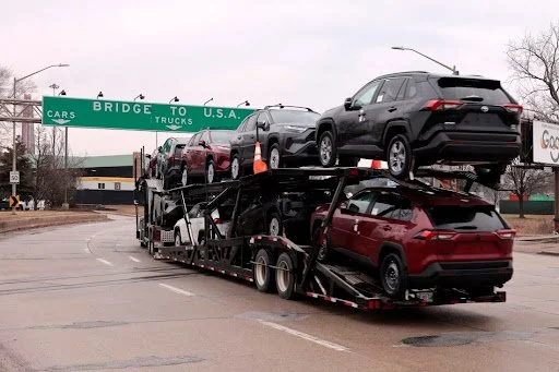 Auto transport carrier hauling vehicles across US border bridge amid tariff policy discussions