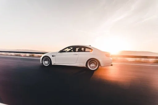 White sports car speeding on highway at sunset, illustrating monthly gas consumption and fuel cost trends for American