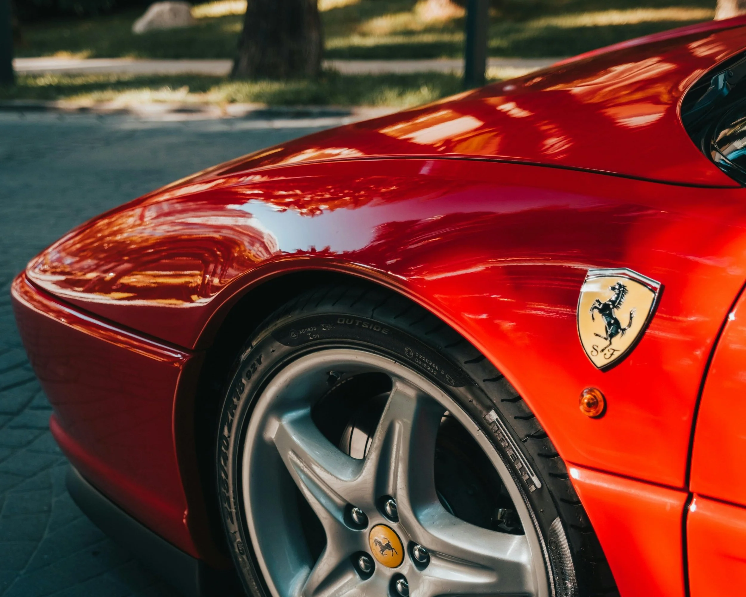 Red Ferrari sports car detail showcasing prancing horse badge and alloy wheel in elevated automotive setting