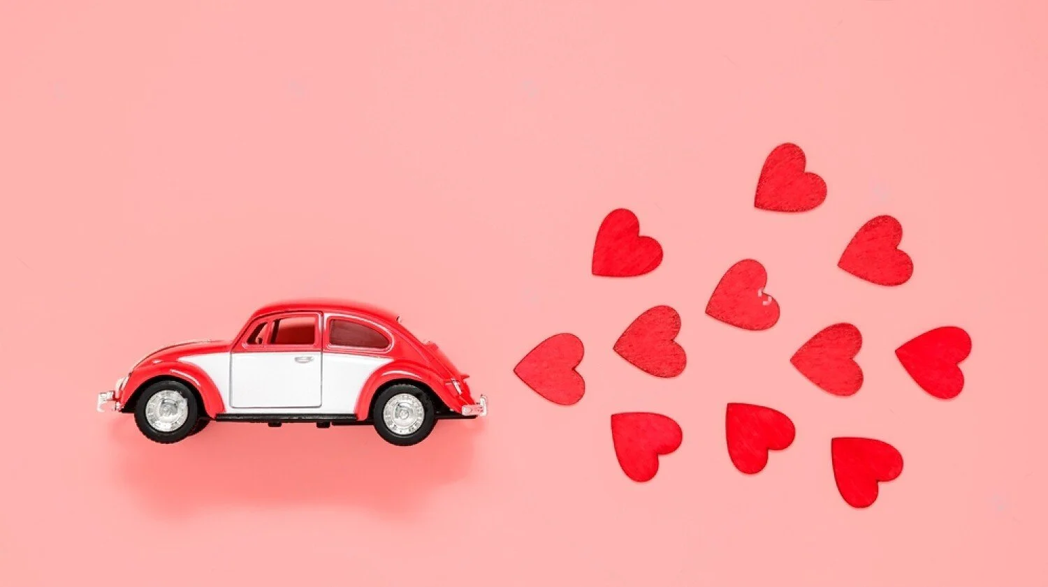 Red and white vintage Beetle with red hearts on pink background, romantic classic car for Valentine's Day date night