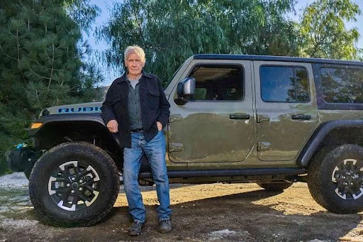 Man poses with green Jeep Wrangler in outdoor setting, featuring vehicle from Super Bowl 2025 commercial