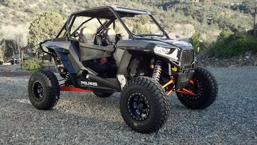 Black side-by-side UTV with roll cage parked on gravel showing street-legal modifications and upgrades needed.
