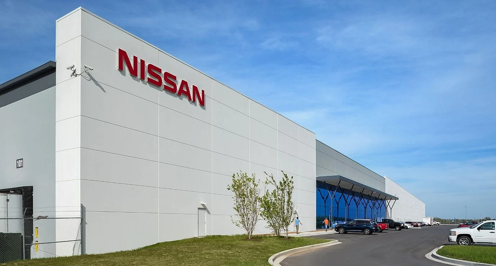 Nissan factory building exterior with white facade and red signage during manufacturing facility closure announcement.