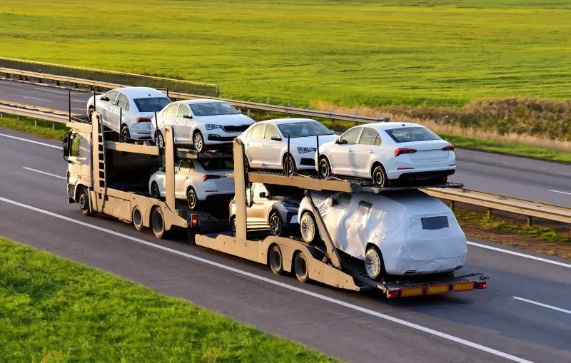 Car carrier transport truck loaded with new vehicles on highway