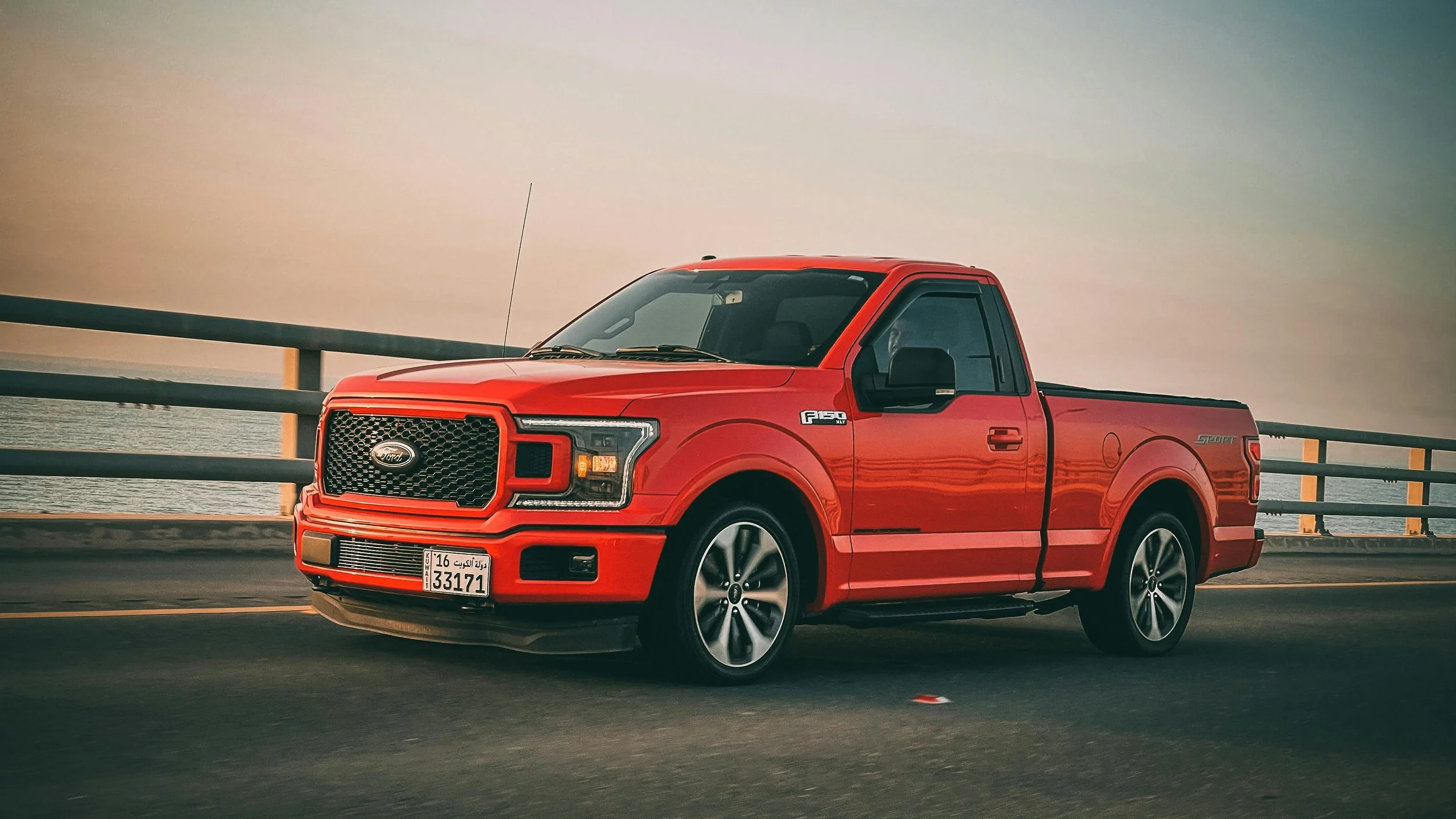 Red Ford F-150 pickup truck parked on bridge, representing delays in next-generation F-150 production announcement