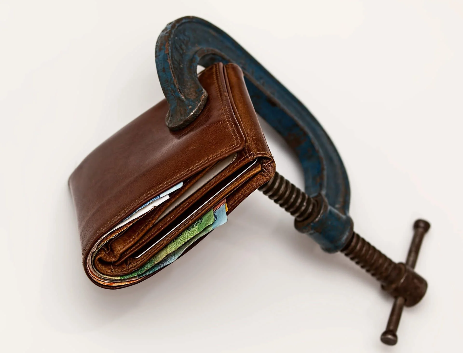 Leather wallet squeezed in vise with cash inside, symbolizing Montana LLC tax deductions for vehicle business expenses