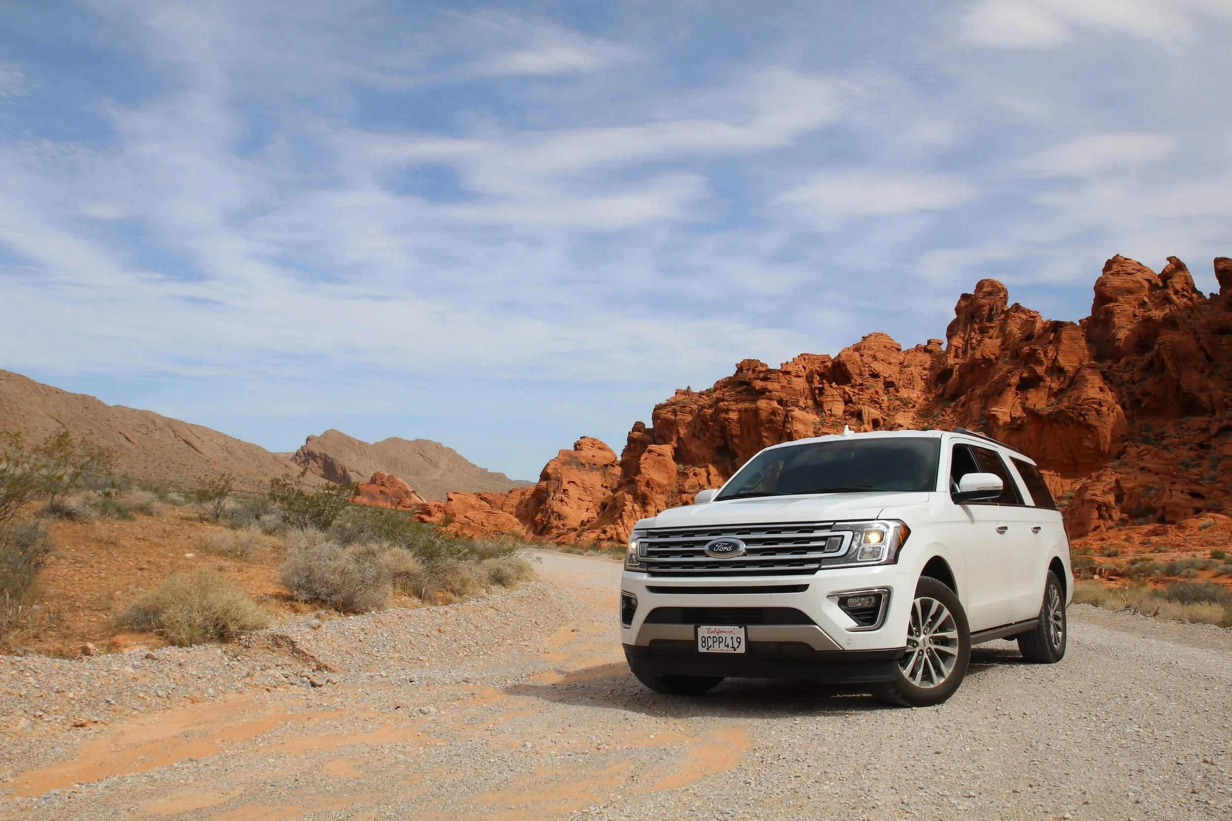 White Ford Expedition SUV parked on desert road with red rock formations