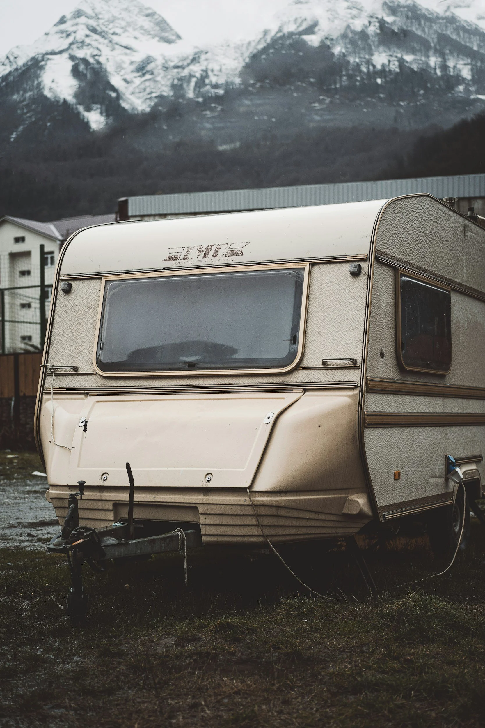 Vintage cream-colored travel trailer parked in mountain landscape, representing nomadic RV living lifestyle