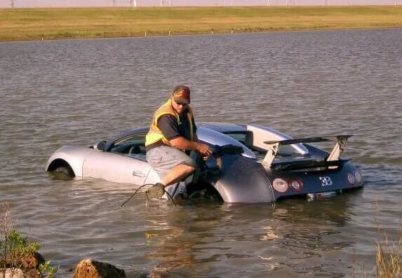 Man in yellow vest rescues submerged car from water, illustrating consequences of title jumping and improper vehicle