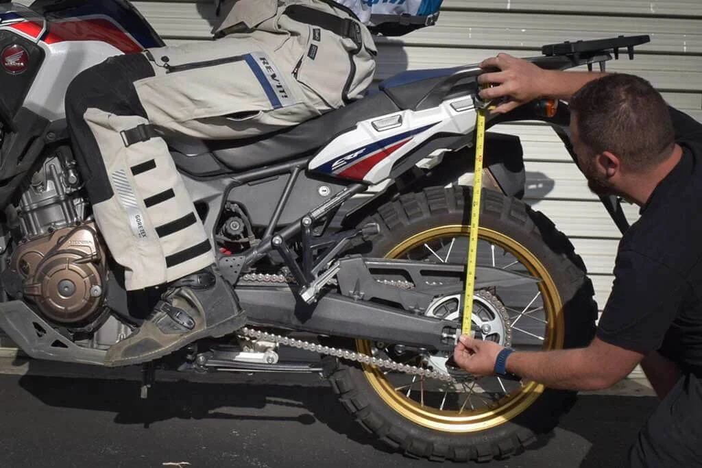 man measuring rear sag dirt bike
