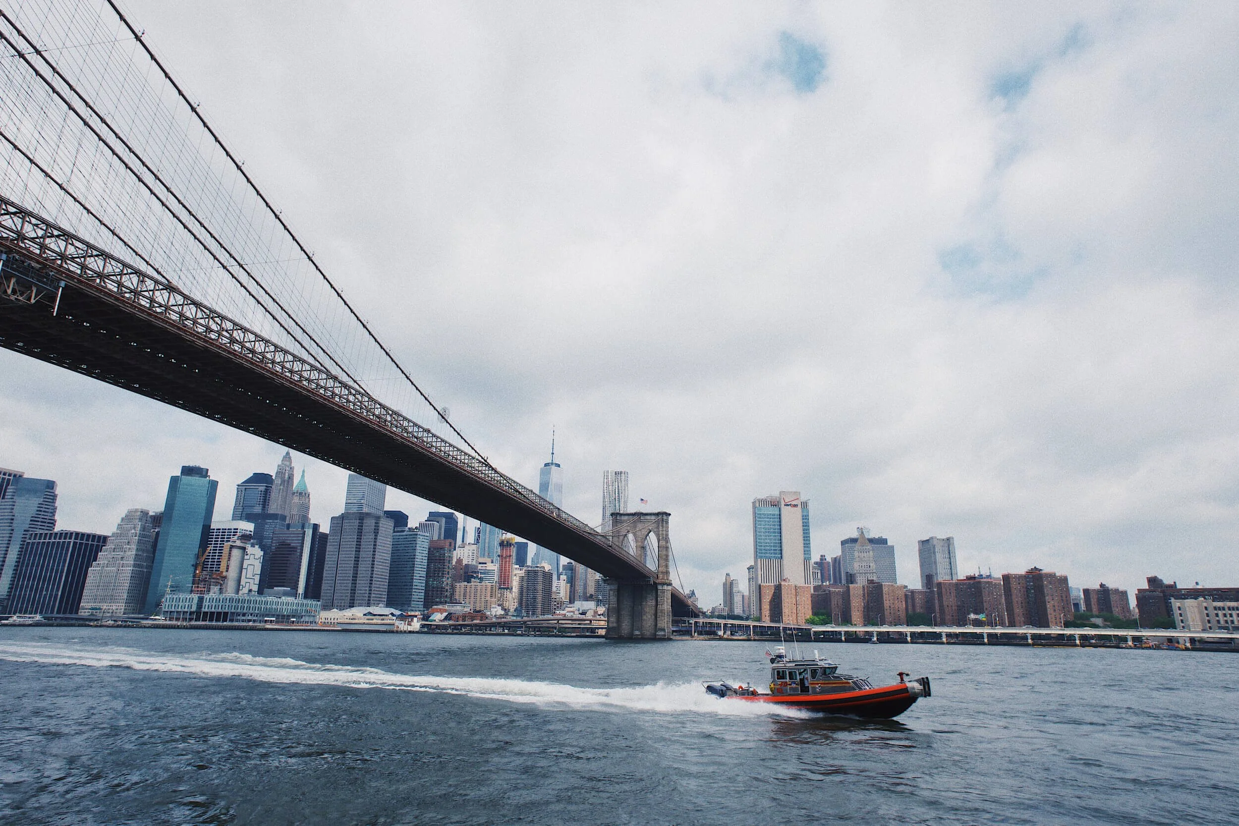A boat going under the Brooklyn Bridge