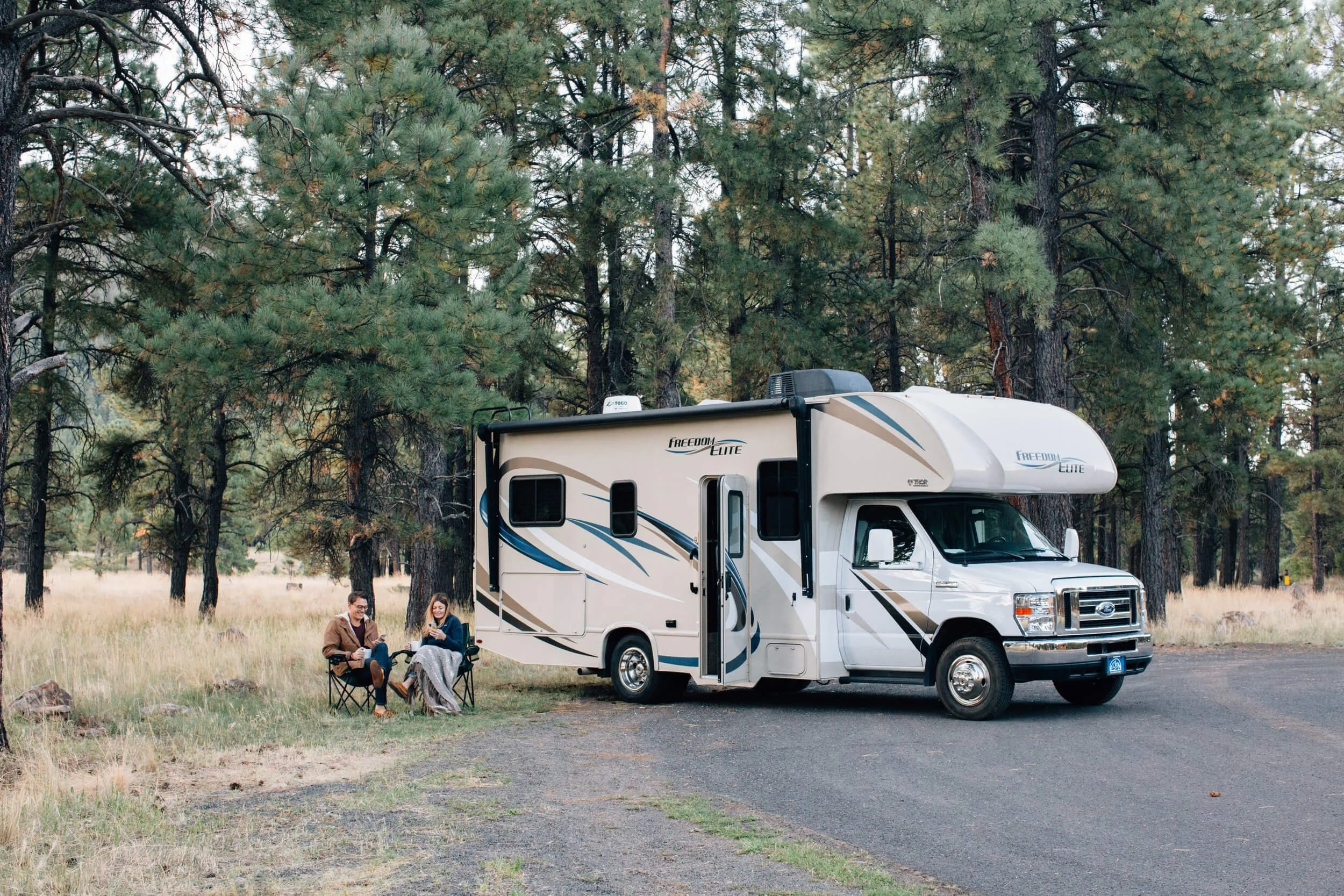 2 persons sitting in front of parked RV