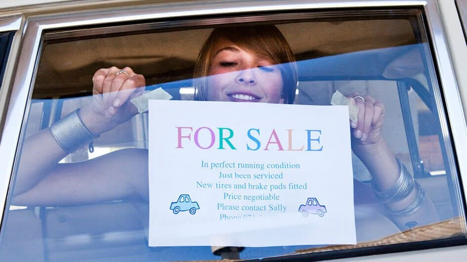 girl selling car for sale sign