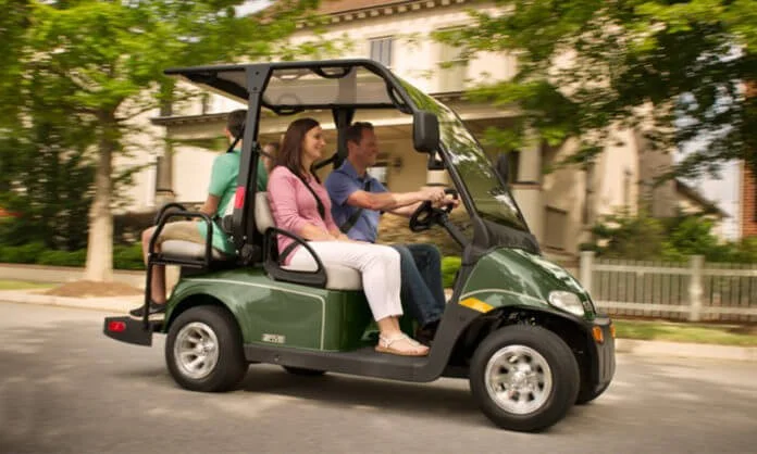 people on golf cart driving on street