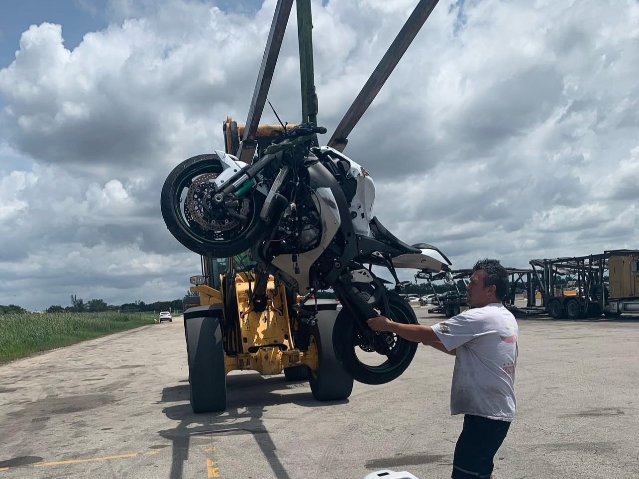 Man securing motorcycle on heavy-duty transport crane for safe motorcycle hauling and accident prevention.