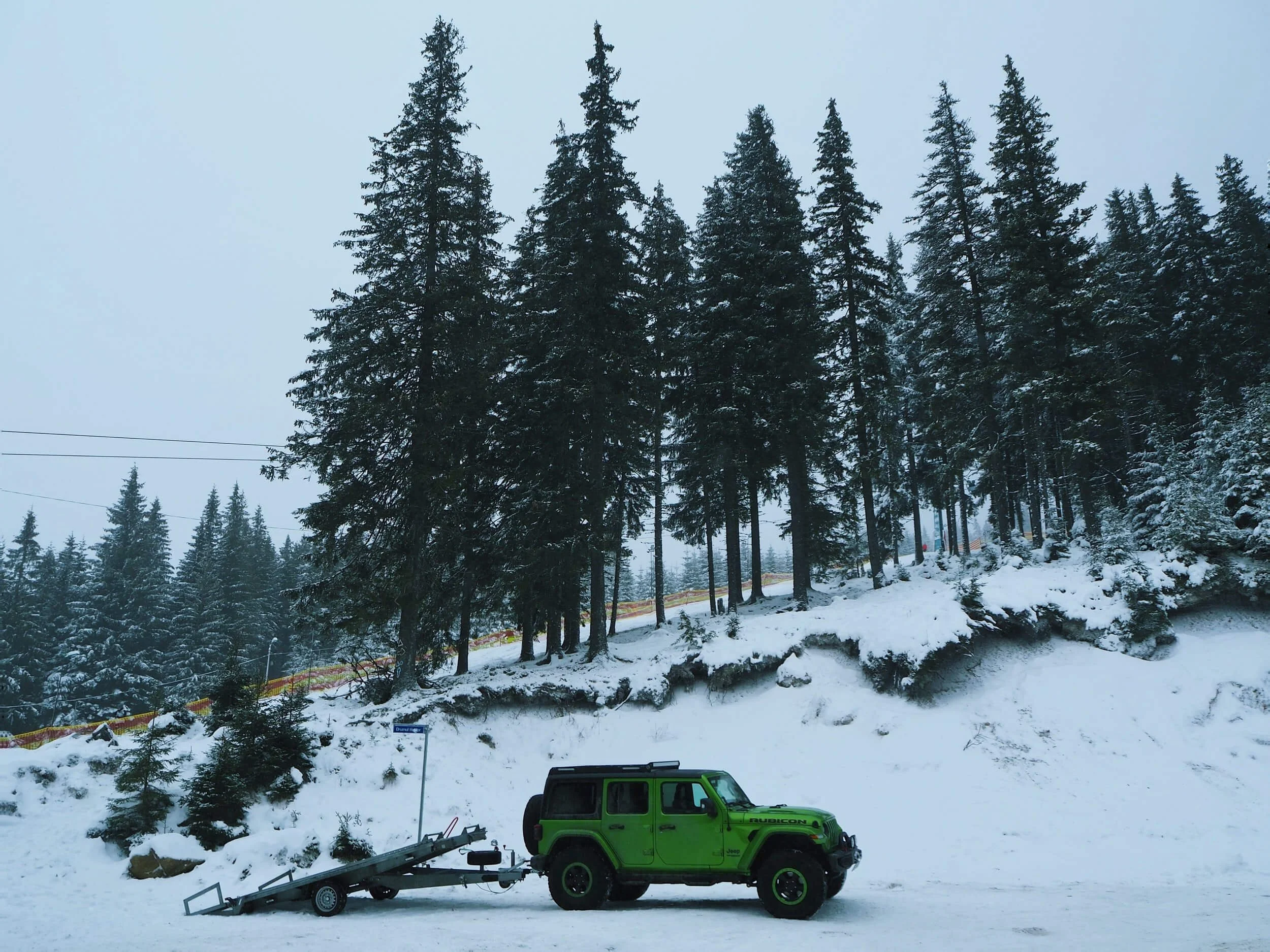 green truck on snow covered area with green trees
