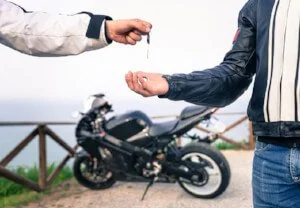 someone giving motorcycle key to another person, motorcycle purchase