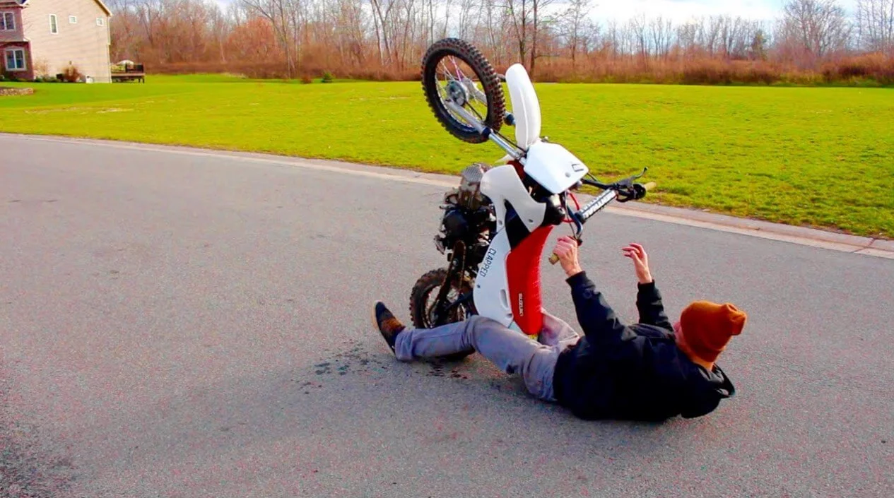 man lying on street with bike wheelie fail