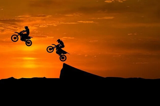2 dirt bikes jumping in the air