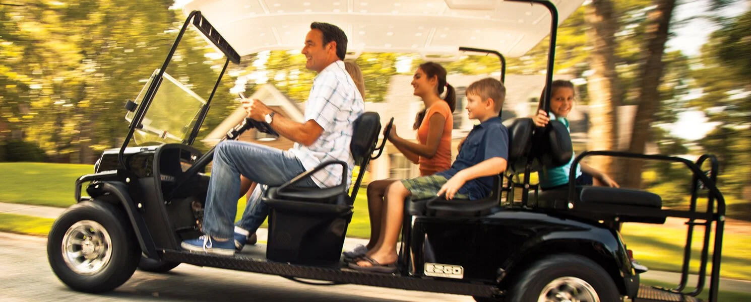 a man driving golf cart with kids