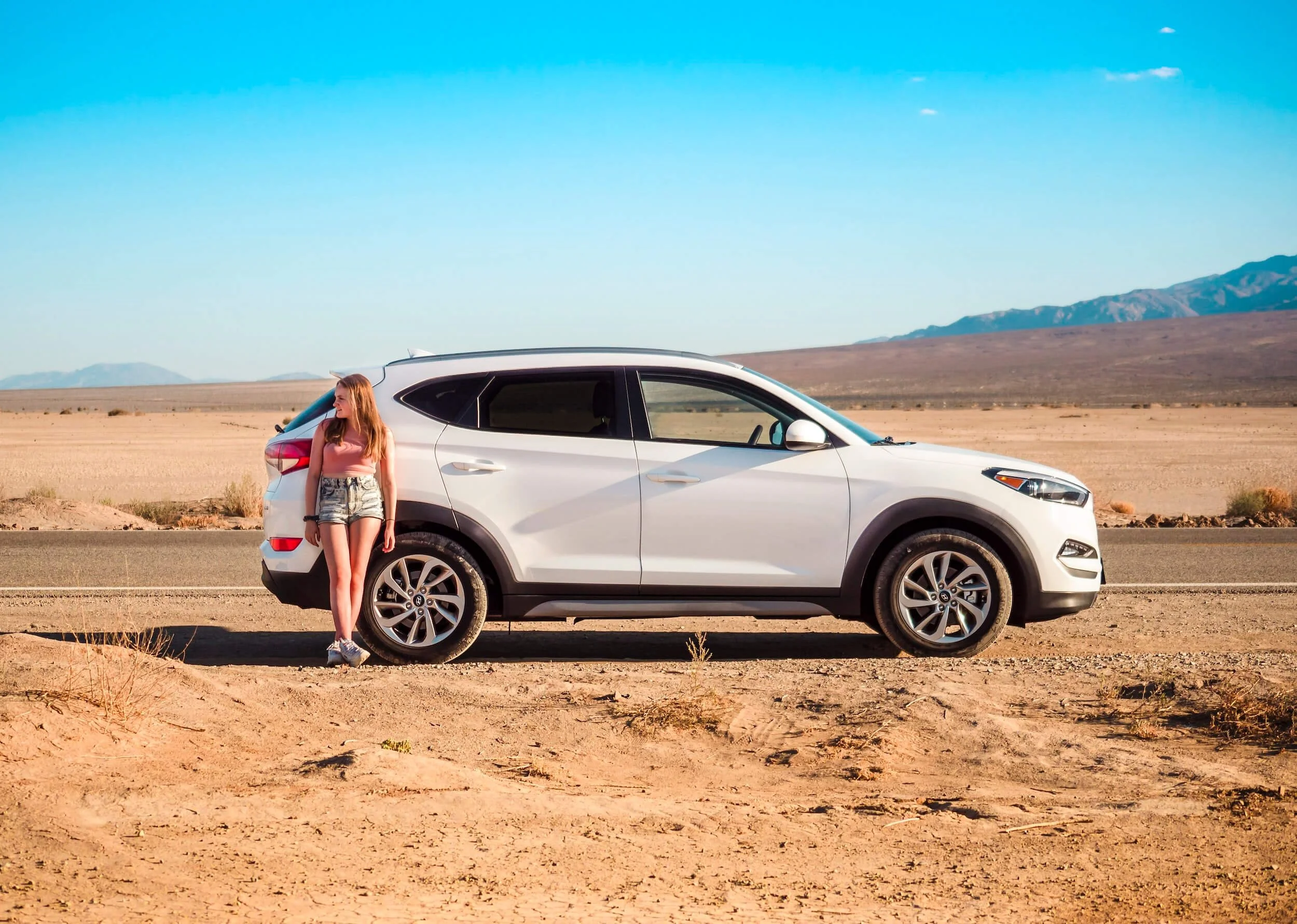 woman sitting beside white suv beside street