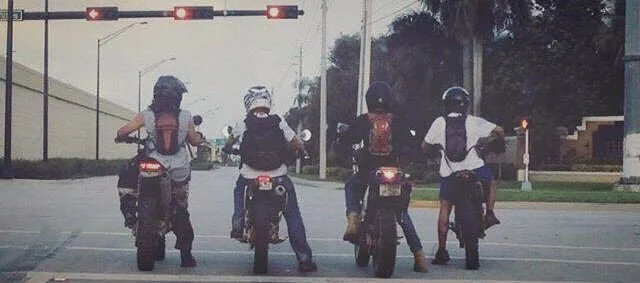 4 dirt bike riders on street