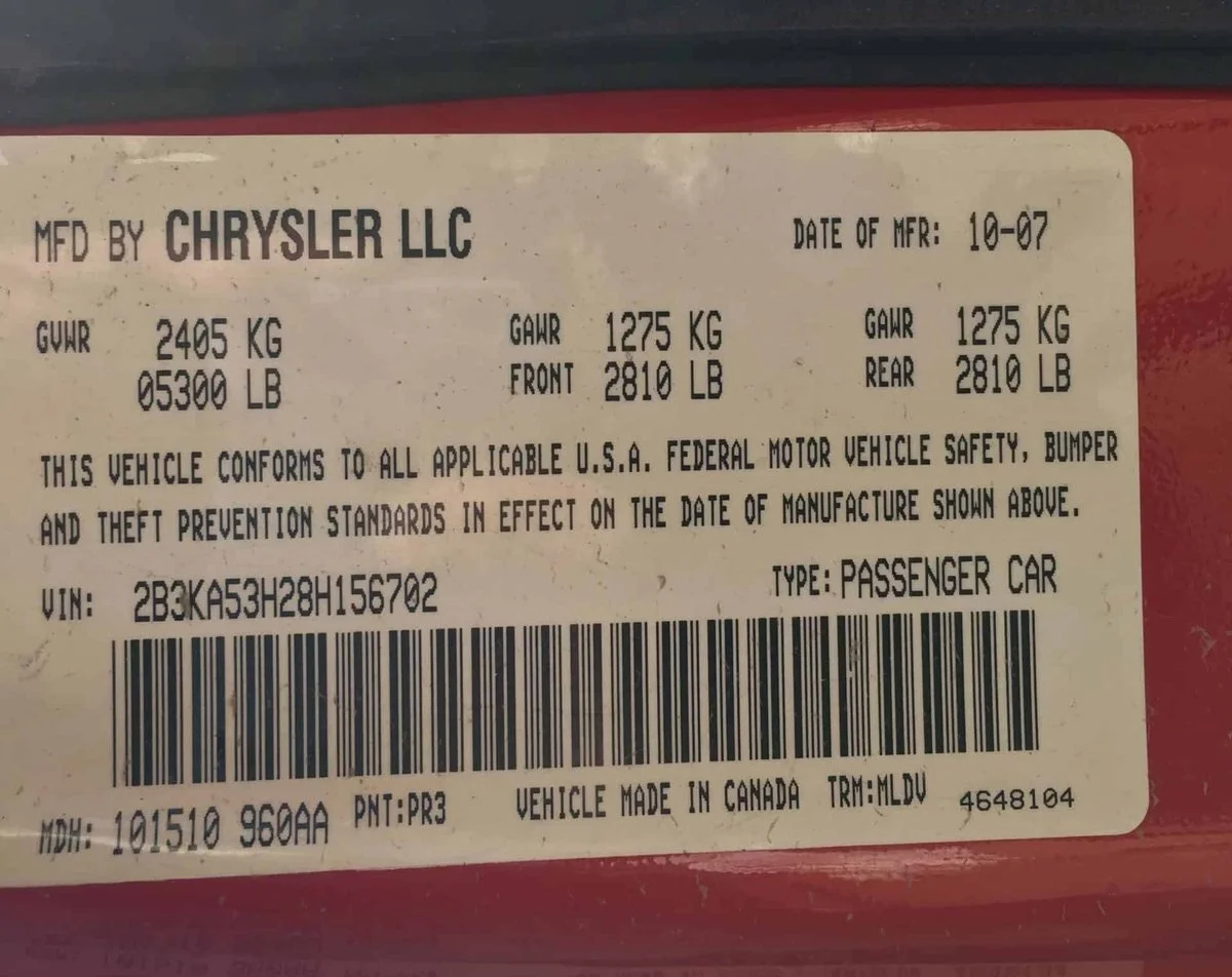 A federal safety certification label on a driver's door jamb with the full VIN readable