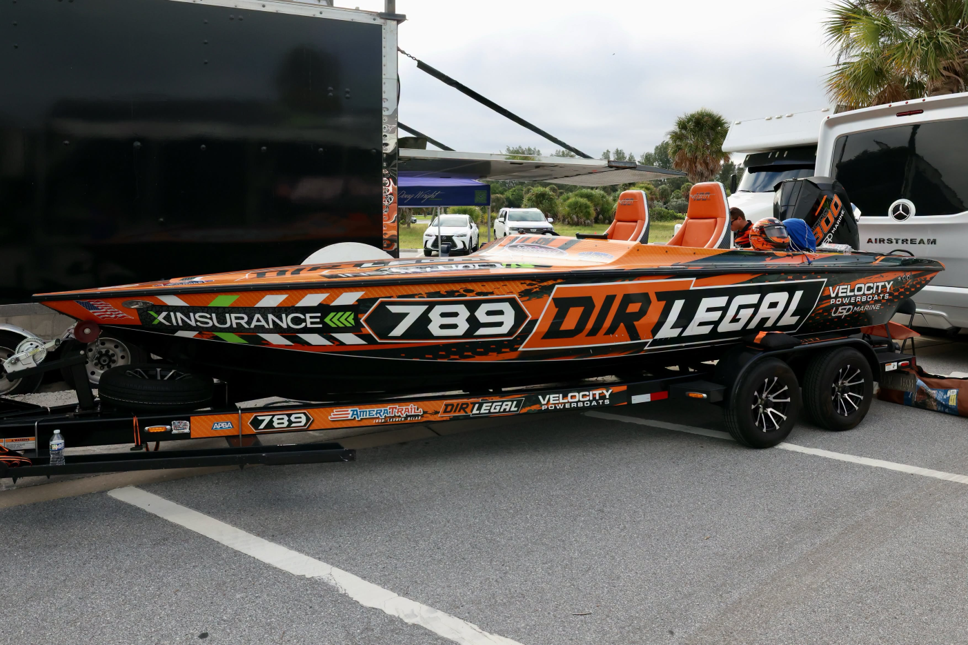 Dirt Legal Velocity #789, an orange and black 22-foot race boat, on its trailer in the dry pits at Clearwater